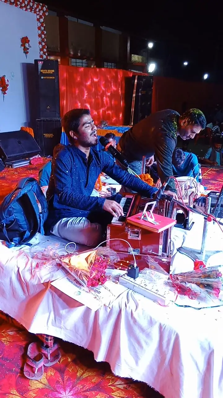 Tripurari Jha singing live on stage while playing the harmonium