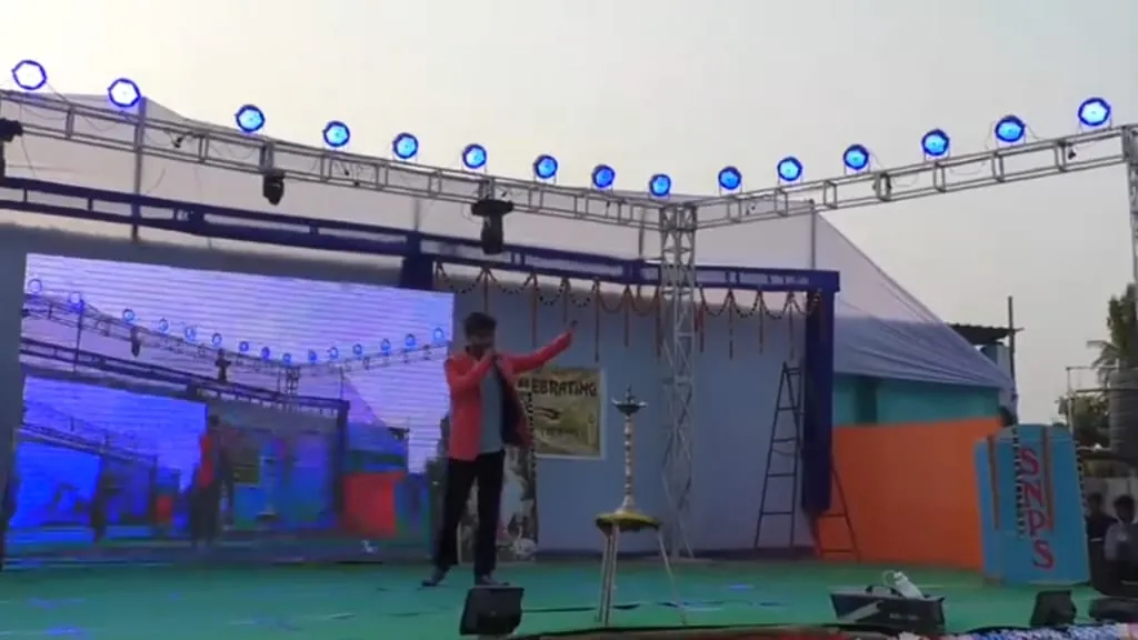 Tripurari Jha performing live on a decorated stage under blue stage lights